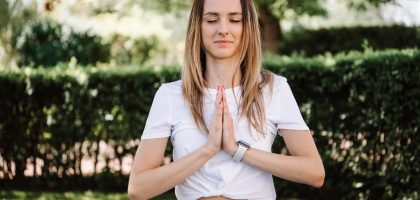 A serene moment of a woman practicing yoga with namaste pose outdoors, embracing mindfulness.